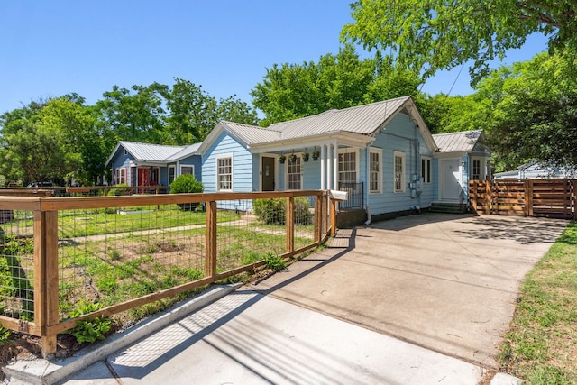 ranch-style home with metal roof, fence, covered porch, and driveway