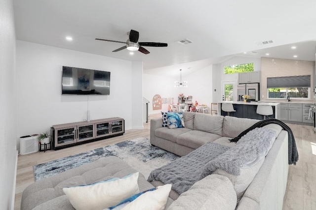 living room with a ceiling fan, a chandelier, recessed lighting, light wood-style flooring, and vaulted ceiling