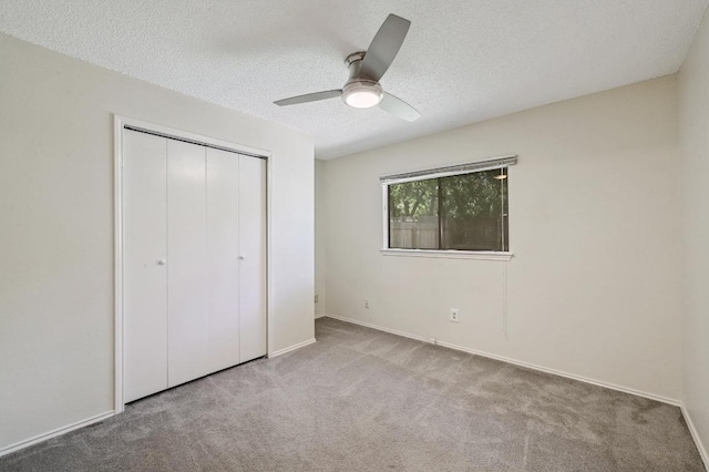 unfurnished bedroom with carpet flooring, a closet, a textured ceiling, ceiling fan, and baseboards