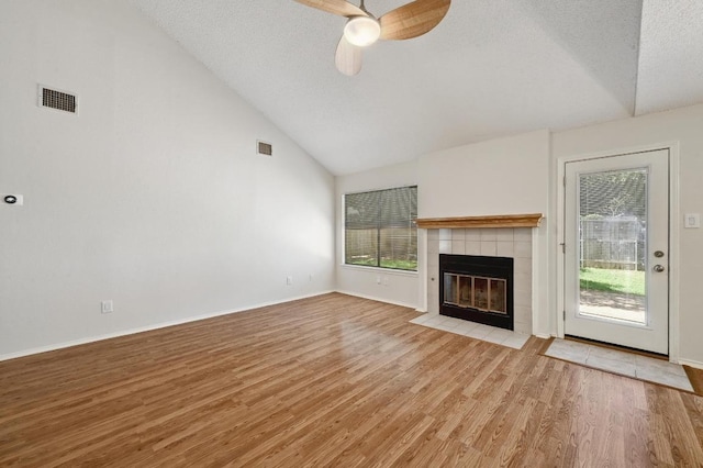 unfurnished living room featuring a tile fireplace, wood finished floors, a ceiling fan, baseboards, and a textured ceiling