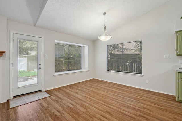 7201 Pine Bluffs Trl, Austin, TX 78729 - unfurnished dining area featuring lofted ceiling, light wood-style floors, baseboards, and a textured ceiling