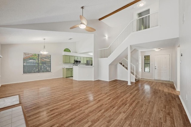 7201 Pine Bluffs Trl, Austin, TX 78729 - unfurnished living room featuring light wood-style floors, high vaulted ceiling, stairway, ceiling fan, and baseboards
