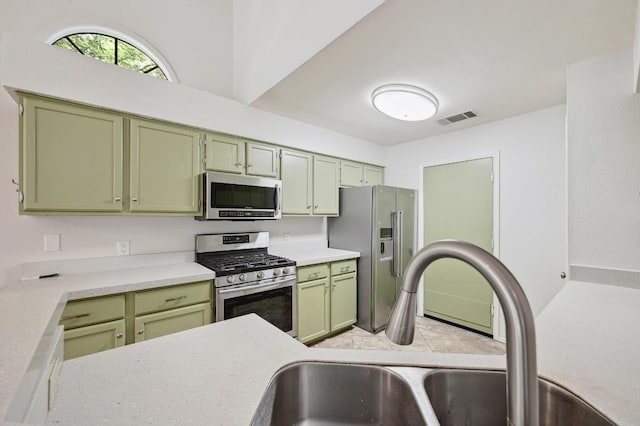 kitchen with appliances with stainless steel finishes, green cabinets, a sink, and light countertops