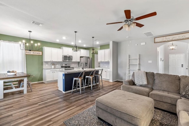 109 Reagor Dr, Taylor, TX 76574 - living room with a chandelier, a ceiling fan, light wood finished floors, arched walkways, and recessed lighting