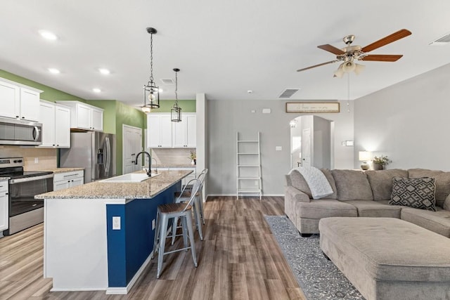 109 Reagor Dr, Taylor, TX 76574 - kitchen featuring appliances with stainless steel finishes, a ceiling fan, arched walkways, open floor plan, and wood finished floors