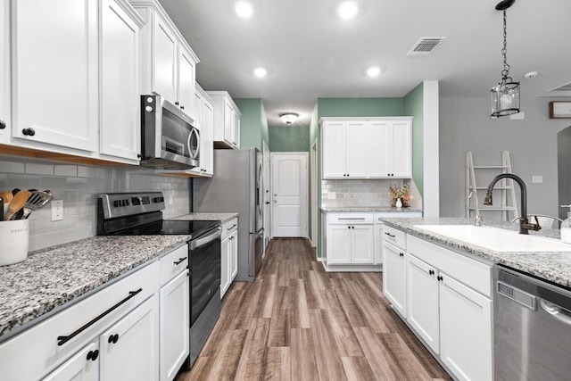 109 Reagor Dr, Taylor, TX 76574 - kitchen featuring appliances with stainless steel finishes, backsplash, white cabinetry, light wood-style flooring, and recessed lighting