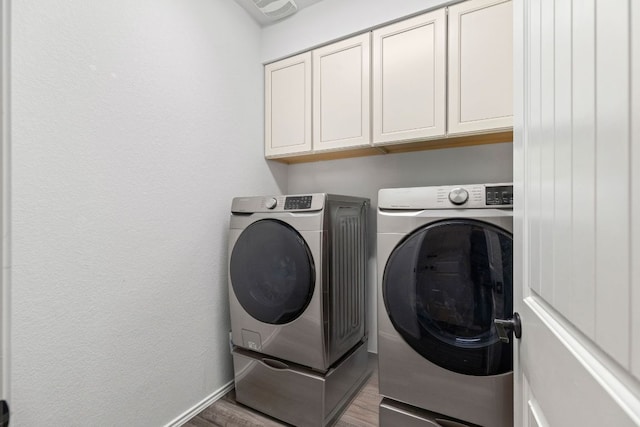 109 Reagor Dr, Taylor, TX 76574 - washroom with washer and clothes dryer, cabinet space, and wood finished floors