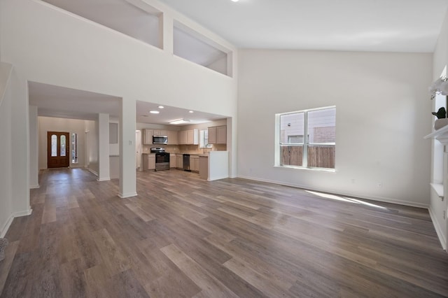 1532 Lorson Loop, Round Rock, TX 78665 - unfurnished living room featuring wood finished floors, baseboards, and a towering ceiling