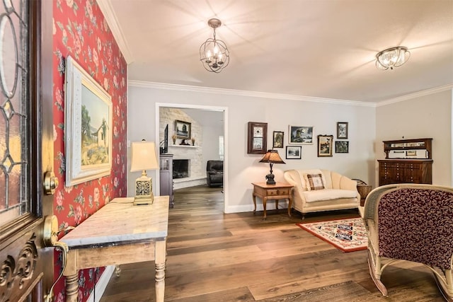 entrance foyer with ornamental molding, wood finished floors, a fireplace with raised hearth, baseboards, and wallpapered walls