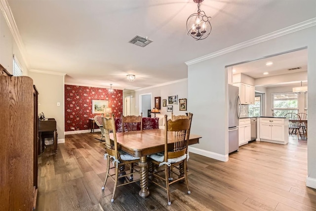 dining space featuring wood finished floors, a chandelier, baseboards, and crown molding