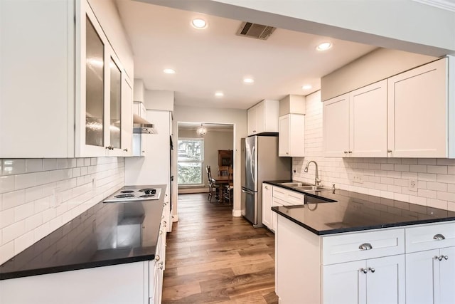 kitchen featuring freestanding refrigerator, dark countertops, a sink, white cabinetry, and recessed lighting