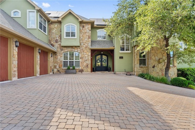 7228 Oak Shores Dr, Austin, TX 78730 - townhome / multi-family property with french doors, stone siding, stucco siding, decorative driveway, and solar panels