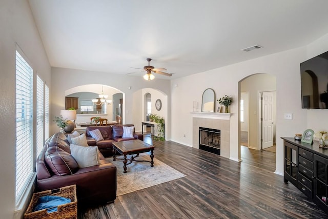 232 Housefinch Loop, Leander, TX 78641 - living room featuring a ceiling fan, dark wood-style floors, arched walkways, a fireplace, and a chandelier