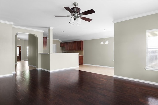 unfurnished living room featuring ornamental molding, ceiling fan, arched walkways, light wood-type flooring, and baseboards