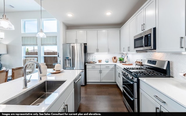 200 Hollister Dr, Liberty Hill, TX 78642 - kitchen with stainless steel appliances, a sink, dark wood-style floors, white cabinets, and pendant lighting