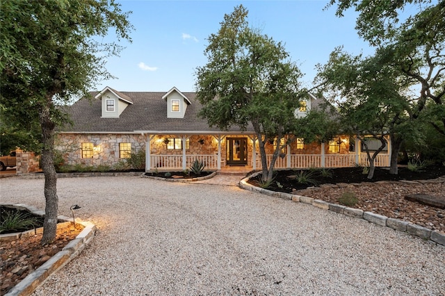 19905 Hamilton Pool Rd, Dripping Springs, TX 78620 - cape cod house with stone siding, a porch, gravel driveway, and a shingled roof