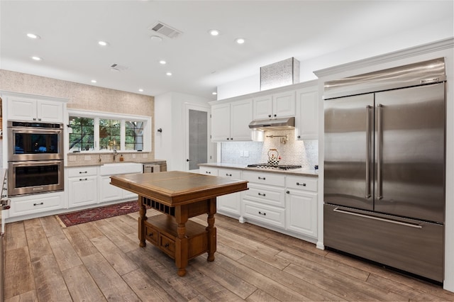 19905 Hamilton Pool Rd, Dripping Springs, TX 78620 - kitchen with appliances with stainless steel finishes, under cabinet range hood, recessed lighting, backsplash, and light wood-type flooring