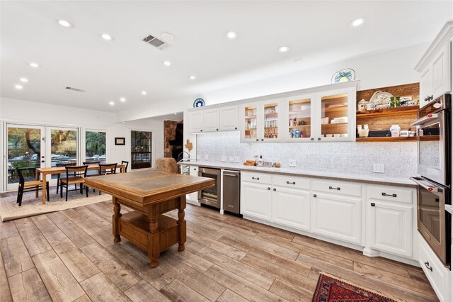19905 Hamilton Pool Rd, Dripping Springs, TX 78620 - kitchen with wine cooler, recessed lighting, decorative backsplash, light wood finished floors, and white cabinetry