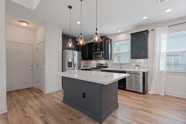6008 Rubicon Run, Austin, TX 78745 - kitchen featuring stainless steel appliances, light wood-style floors, a sink, a center island, and recessed lighting