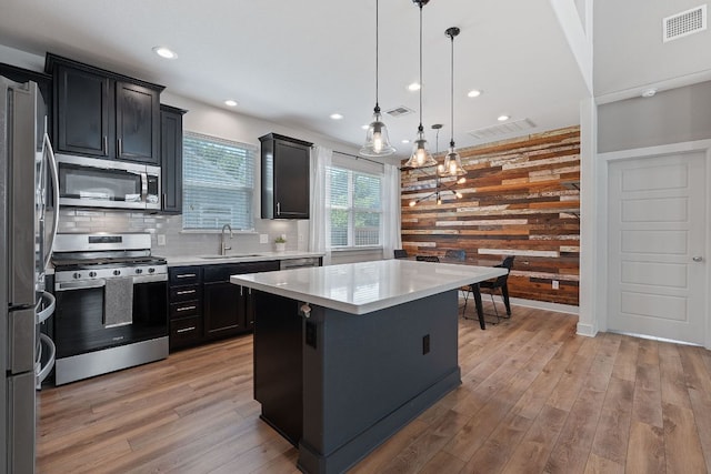 6008 Rubicon Run, Austin, TX 78745 - kitchen featuring stainless steel appliances, a sink, a kitchen island, light wood-style flooring, and backsplash