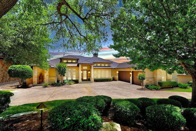 view of front of property featuring concrete driveway, a garage, metal roof, a standing seam roof, and stone siding