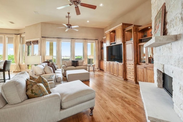 living room featuring a ceiling fan, light wood-style flooring, a stone fireplace, and recessed lighting