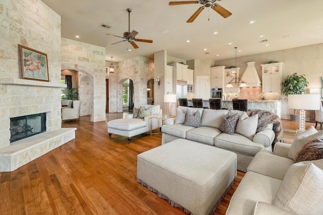 living room featuring arched walkways, ceiling fan, wood finished floors, a fireplace, and recessed lighting