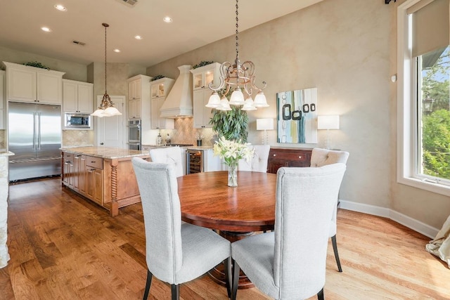 dining room with wine cooler, wood finished floors, recessed lighting, a chandelier, and baseboards