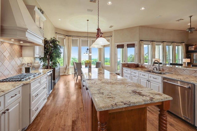 kitchen featuring custom exhaust hood, stainless steel appliances, a sink, healthy amount of natural light, and recessed lighting