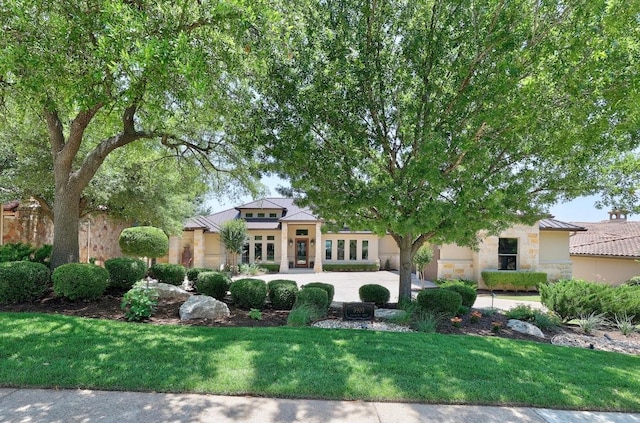 view of front of house featuring stone siding, a front yard, a standing seam roof, and stucco siding