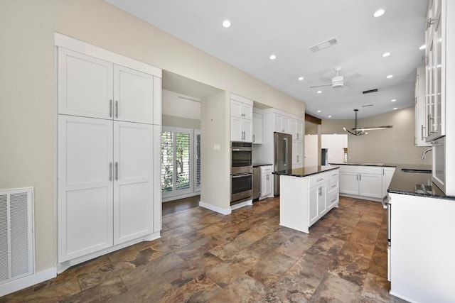 107 Phalarope Dr, Buda, TX 78610 - kitchen featuring a ceiling fan, a center island, appliances with stainless steel finishes, stone finish flooring, and white cabinets