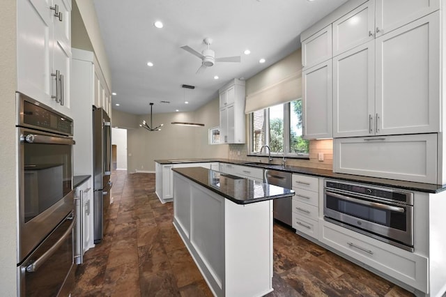 107 Phalarope Dr, Buda, TX 78610 - kitchen featuring appliances with stainless steel finishes, a sink, a peninsula, stone finish floors, and decorative backsplash