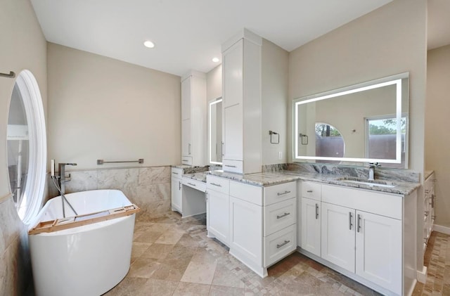 107 Phalarope Dr, Buda, TX 78610 - bathroom featuring tile walls, a freestanding bath, vanity, recessed lighting, and a wainscoted wall