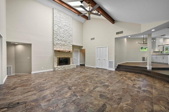 107 Phalarope Dr, Buda, TX 78610 - unfurnished living room featuring high vaulted ceiling, ceiling fan, a stone fireplace, beamed ceiling, and baseboards