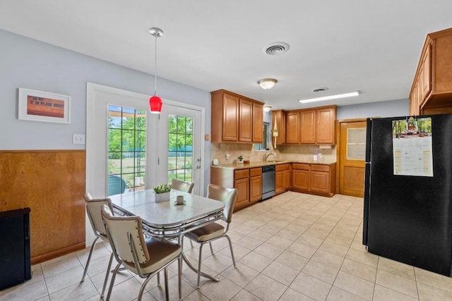 7912 Burrell Dr, Austin, TX 78757 - kitchen featuring freestanding refrigerator, stainless steel dishwasher, light tile patterned floors, backsplash, and brown cabinets