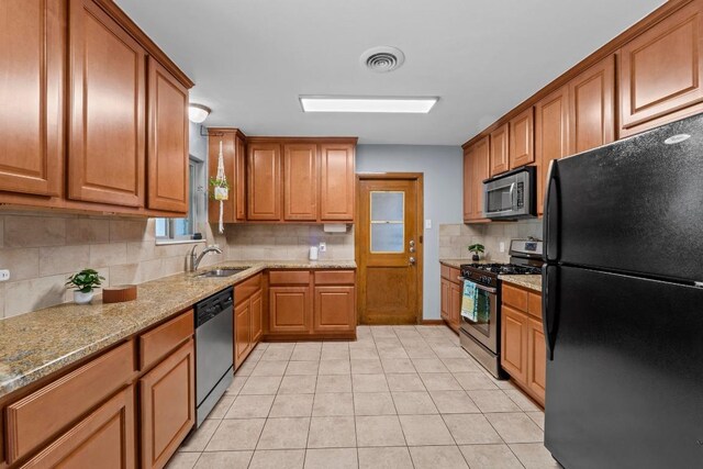 7912 Burrell Dr, Austin, TX 78757 - kitchen with stainless steel appliances, a sink, backsplash, light stone counters, and brown cabinetry