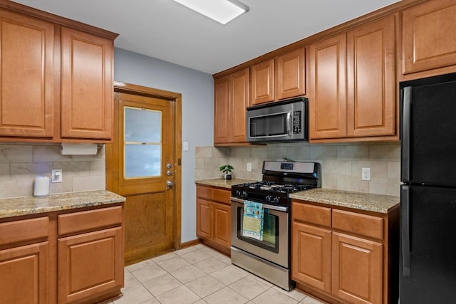 7912 Burrell Dr, Austin, TX 78757 - kitchen featuring appliances with stainless steel finishes, decorative backsplash, light tile patterned floors, and brown cabinets