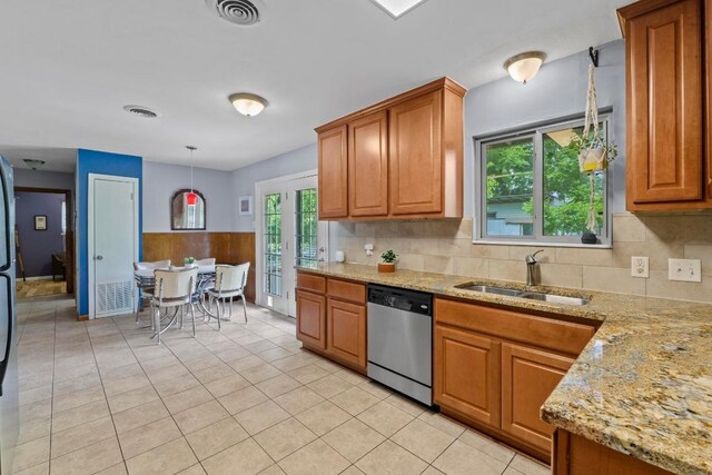 7912 Burrell Dr, Austin, TX 78757 - kitchen featuring stainless steel dishwasher, brown cabinetry, a sink, light stone counters, and wainscoting