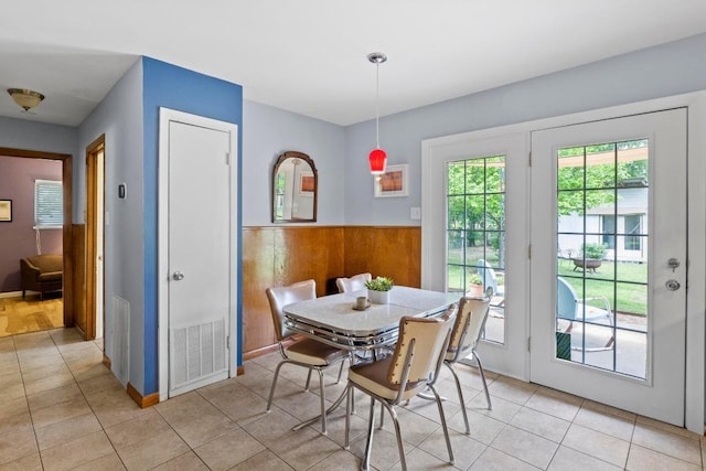 7912 Burrell Dr, Austin, TX 78757 - dining area with light tile patterned floors, a wainscoted wall, and wood walls