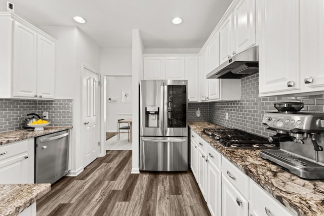 7016 Bending Oak Rd, Austin, TX 78749 - kitchen with appliances with stainless steel finishes, under cabinet range hood, white cabinetry, dark wood-style flooring, and tasteful backsplash