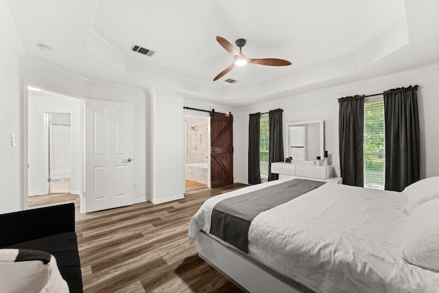 7016 Bending Oak Rd, Austin, TX 78749 - bedroom featuring a raised ceiling, a barn door, ornamental molding, wood finished floors, and connected bathroom