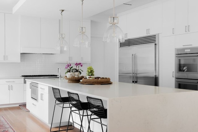 1800 Bay Hill Dr, Austin, TX 78746 - kitchen with stainless steel appliances, light countertops, decorative backsplash, and white cabinetry