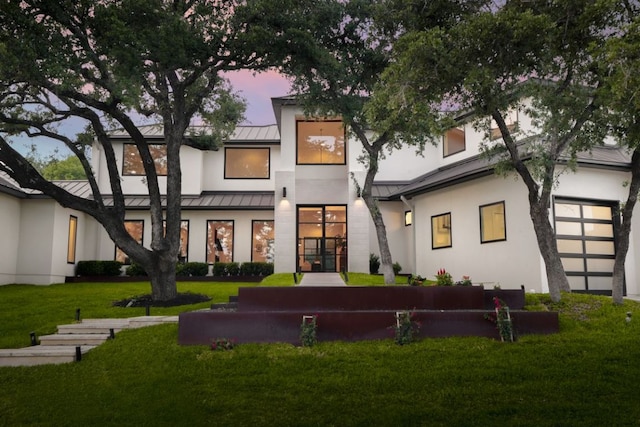 1800 Bay Hill Dr, Austin, TX 78746 - back of house at dusk featuring a standing seam roof, metal roof, stucco siding, and a yard