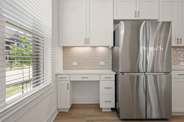3109 Sorin St, Austin, TX 78723 - kitchen featuring freestanding refrigerator, backsplash, light wood-style flooring, baseboards, and white cabinetry
