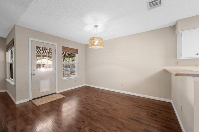 13018 Garfield Ln, Austin, TX 78727 - unfurnished dining area with dark wood finished floors, baseboards, and a textured ceiling