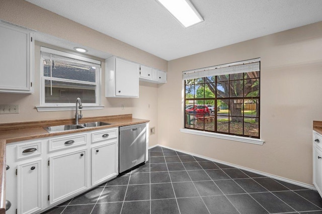 13018 Garfield Ln, Austin, TX 78727 - kitchen with stainless steel dishwasher, a sink, white cabinetry, and baseboards