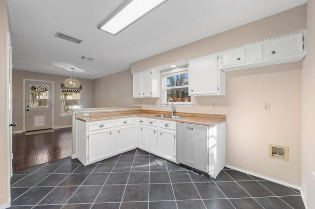 kitchen with dishwasher, a peninsula, white cabinets, and dark tile patterned flooring