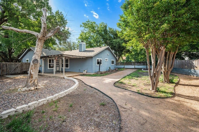 back of property with a chimney, a patio, a fenced backyard, and a pergola