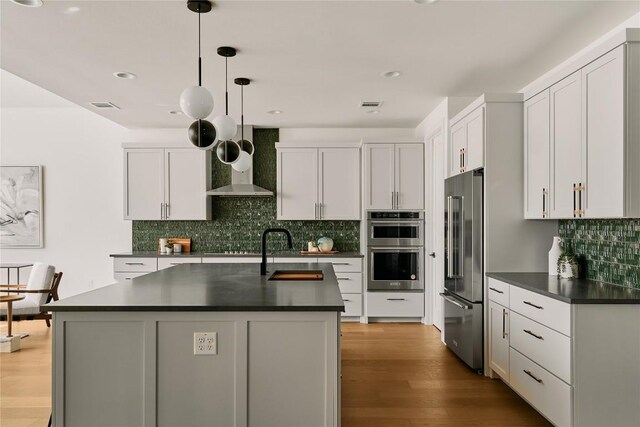 5805 Mojave Dr, Austin, TX 78745 - kitchen featuring stainless steel appliances, a sink, dark countertops, wood finished floors, and decorative backsplash