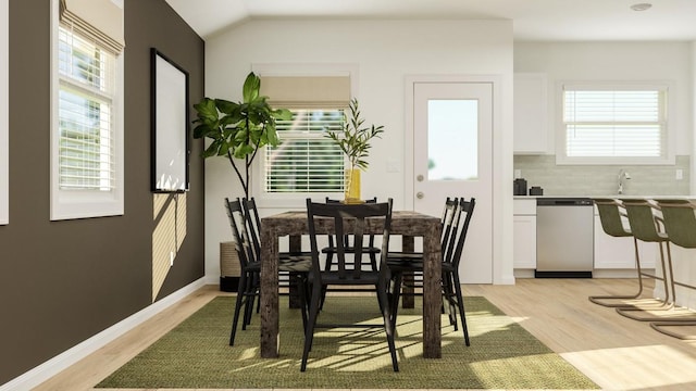 dining room with light wood finished floors, healthy amount of natural light, and lofted ceiling